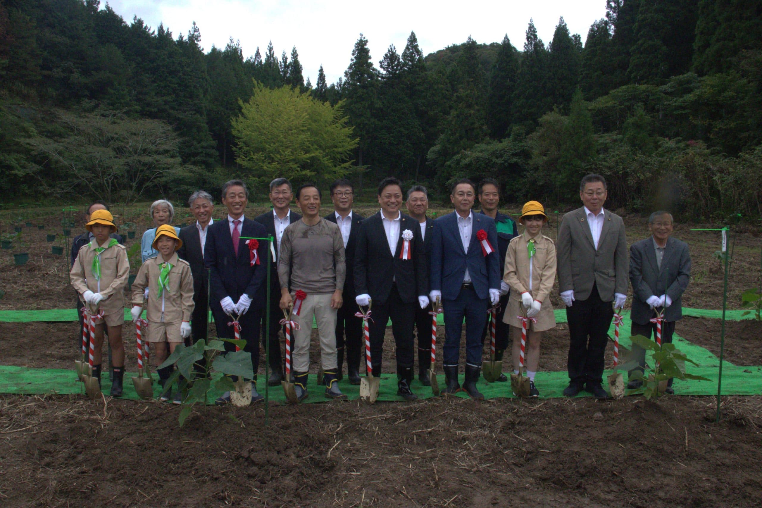 菩提町の圃場での植樹式。市長・市議・緑の少年団・地域住民ら約15名がスコップを持って一列に並ぶ集合写真